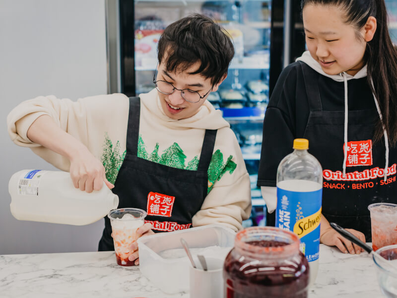 Two people mixing and pouring ingredients to make bubble tea